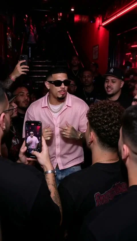 Performer surrounded by fans under red nightclub lights